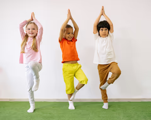 Three happy children, each standing on one foot.